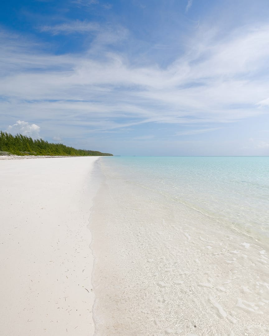 A white sand beach, with clear skies, and turquoise water